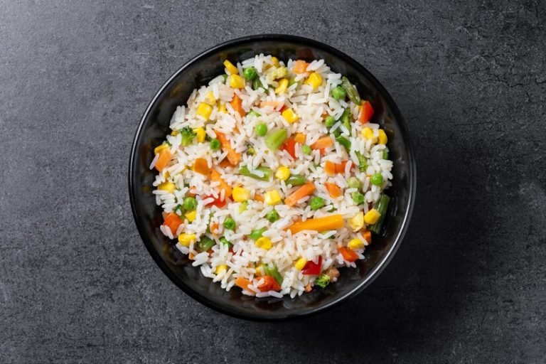 white-rice-with-vegetables-black-bowl-wooden-table_123827-31645